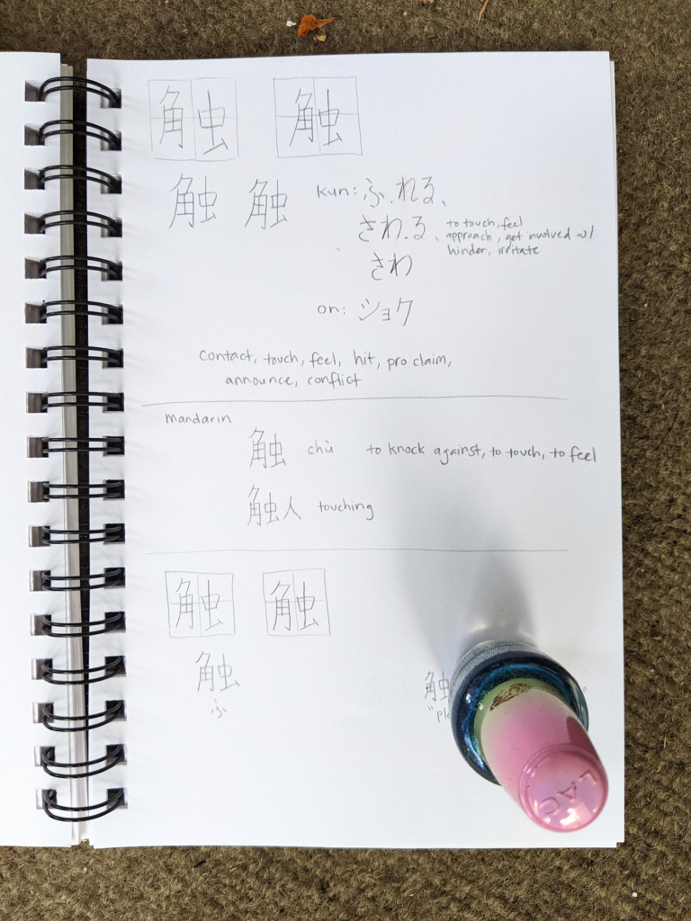 A photo of a sketchbook page with kanji practice and Japanese-English word definitions on it